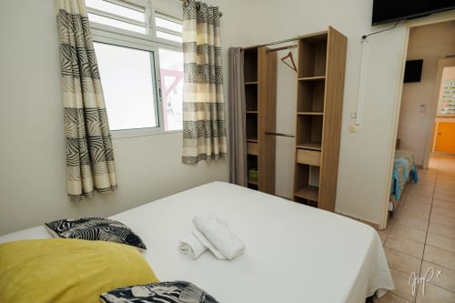 Chambre de la Villa Lueur du Sud à Otantik Caribbean avec lit blanc, armoire en bois et rideaux à motifs zèbre