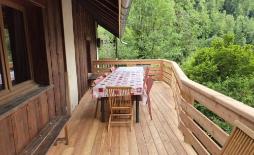 Terrasse en bois du Gîte Les Boleros avec table, chaises et vue sur la forêt à Queige
