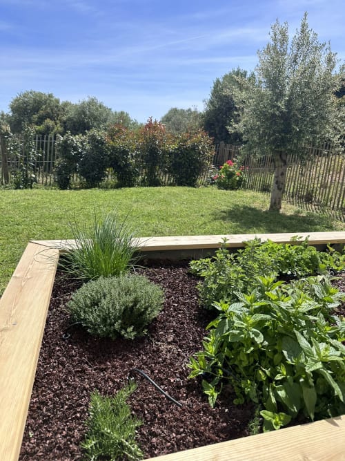 Jardinière surélevée avec herbes et plantes à l'appartement La Poudrière à Figari, avec pelouse et jardin clos au-delà