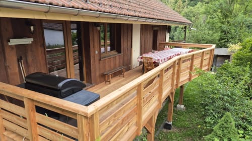 Terrasse en bois du gîte Les Boleros à Queige avec vue montagne et verdure environnante