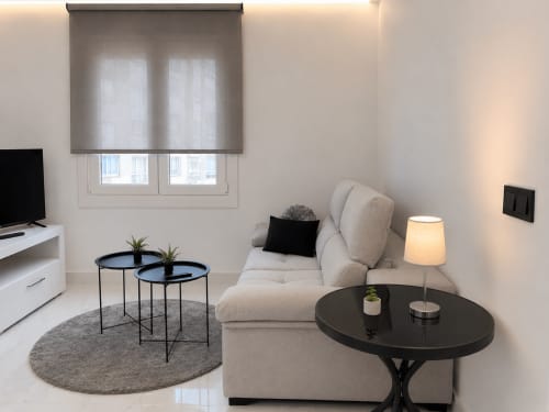 Sala moderna del apartamento Antia Mare en Baiona con sofá beige, mesillas negras y vistas a la ciudad