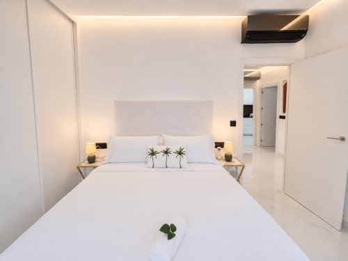 Dormitorio moderno y luminoso en apartamento Antia Mare, Baiona, con decoración minimalista, planta de palmera y aire acondicionado