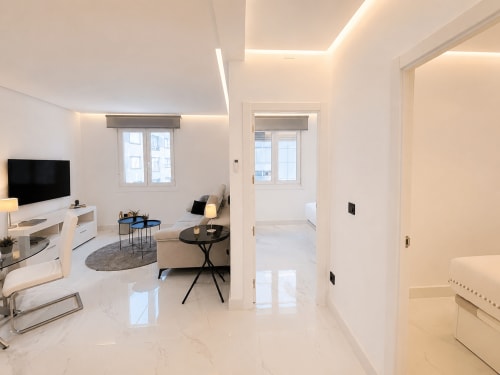 Elegante salón con suelos de mármol, televisor, zona de estar y puertas de cristal en el apartamento Antia Mare, Baiona