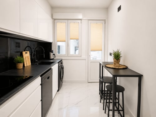 Cocina moderna con encimeras negras, muebles blancos y barra en el apartamento Antia Mare de Baiona