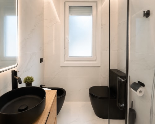 Baño moderno en apartamento Antia Mare, Baiona con accesorios negros y baldosas de mármol