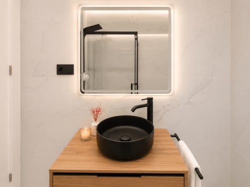 Baño moderno en apartamento Antia Mare, Baiona con lavabo negro, espejo LED y tocador de madera