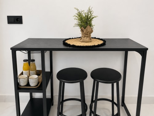 Mesa bar negra moderna con dos taburetes y planta en maceta, apartamento Antia Mare en Baiona