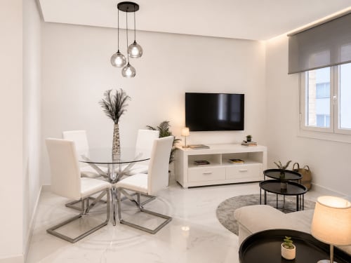 Sala de estar moderna en el apartamento Antia Mare de Baiona con comedor, televisor, lámparas colgantes y mobiliario contemporáneo