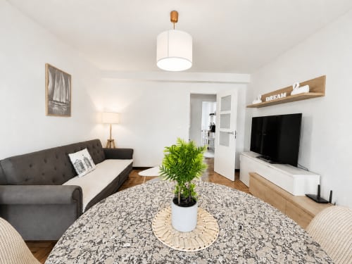 Sala moderna de apartamento familiar en Baiona con sofá gris, televisor, estantes de madera y planta en maceta