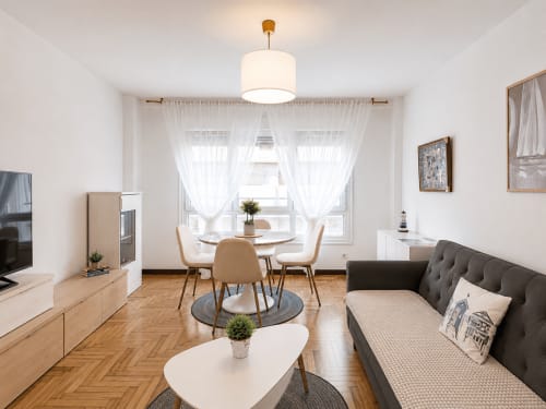 Moderno apartamento familiar en Baiona con sala de estar, comedor, sofá gris, suelos de madera y vistas al mar