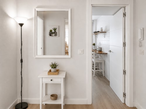 Pasillo moderno en apartamento Morriña, Holibai Baiona, con espejo blanco, tocador y puerta de cocina abierta