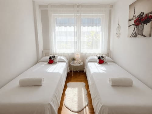 Luminoso dormitorio doble con vistas al mar en el apartamento Morriña de Holibai, apto para mascotas, en Baiona. Ropa de cama blanca, suelo de madera, amplio