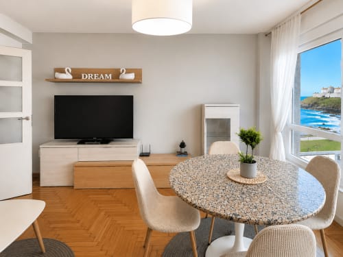Moderno salón de apartamento con comedor, TV y vistas al mar en el hotel Holibai de Baiona, España