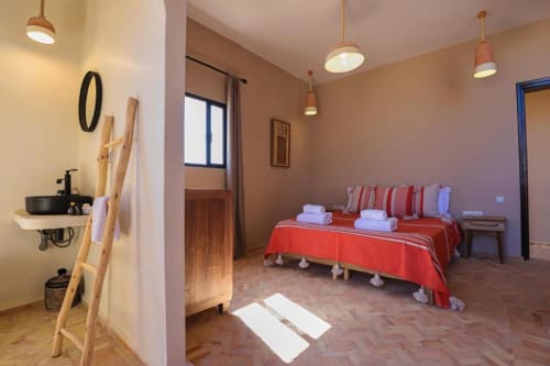 Chambre Sirocco at Riad Arkaya in Essaouira with red bedspread, en-suite bathroom, and pendant lighting