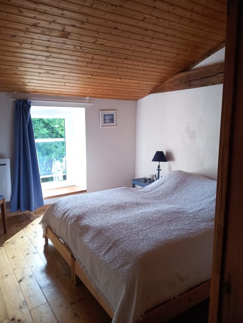 Chambre spacieuse aux poutres apparentes, vue sur le jardin et lit accessible au gîte La Faerie à Grand'landes
