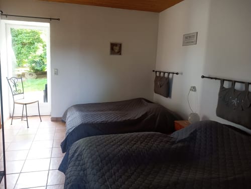 Chambre PMR accessible du gîte La Faerie à Grand'landes avec deux lits, porte-fenêtre sur jardin et équipements modernes