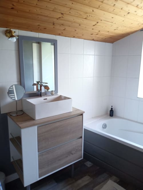 Salle de bains moderne et accessible du gîte La Faerie en Grand'landes avec vasque blanche, miroir, baignoire et plafond en bois