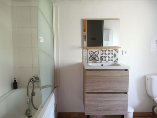 Salle de bain moderne du gîte La Faerie avec meuble vasque en bois, carrelage à motifs et douche à Grand'landes