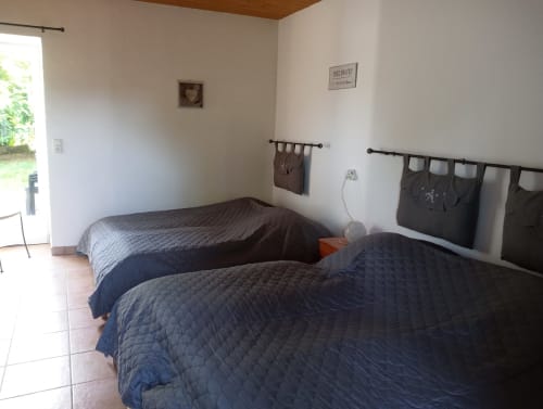 Chambre lumineuse avec deux lits jumeaux, têtes de lit noires et literie matelassée bleue au gîte La Faerie, Grand'landes