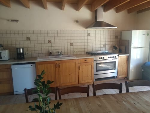 Cuisine rustique du gîte La Faerie, Grand'landes, avec poutres en bois, crédence carrelée et électroménagers modernes