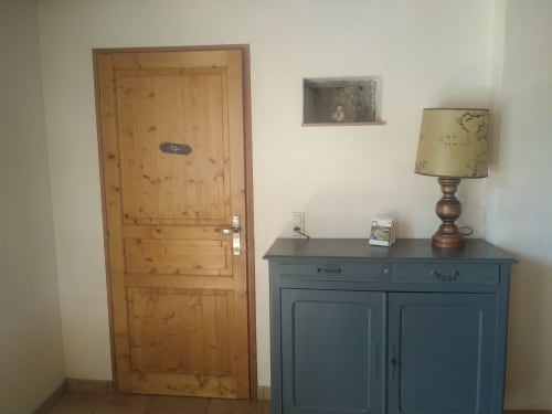 Entrée du cottage à La Faerie avec porte en bois, armoire bleue, lampe et vue sur le jardin à Grand'landes