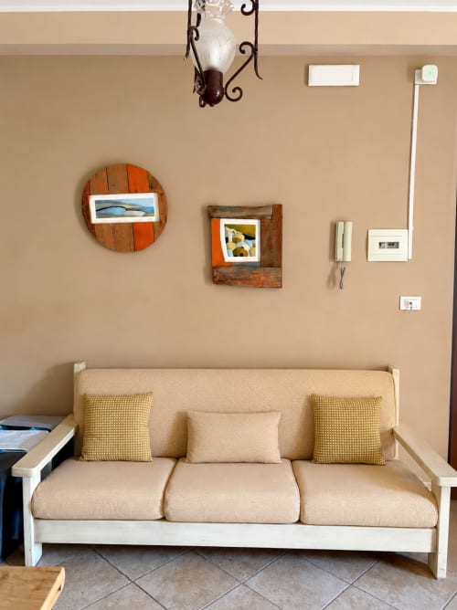 Divano beige con cuscini gialli nell'appartamento siciliano In Home, arredato con quadri in cornice di legno e dettagli vintage