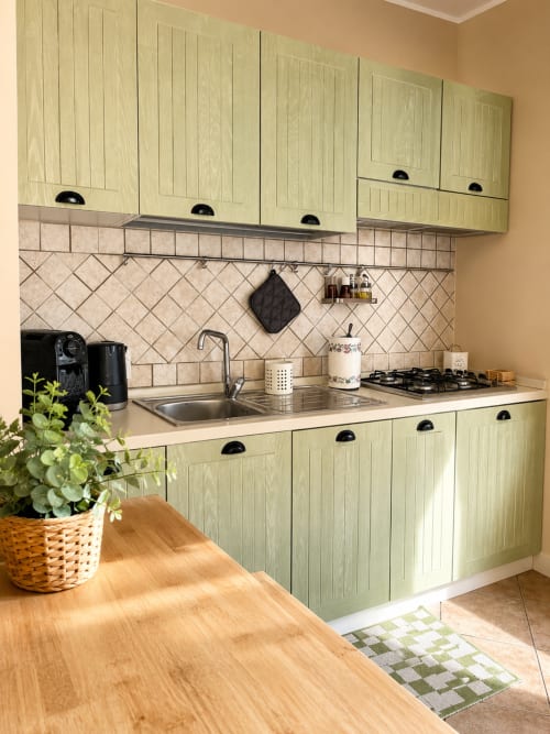 Cucina moderna con cabinetry verde chiaro, elettrodomestici in acciaio inox e piastrelle diagonali in Sicilia In Home