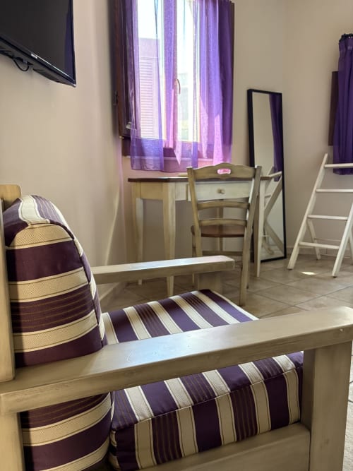 Accogliente appartamento a Catania con arredamento a righe viola e crema, mobili da pranzo in legno e tende viola con vista sulla città