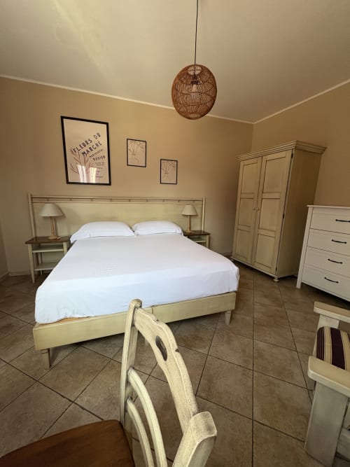 Camera luminosa di Sicily In Home con letto matrimoniale, lampada a sospensione in legno, arredi chiari e pavimentazione in maioliche a Catania