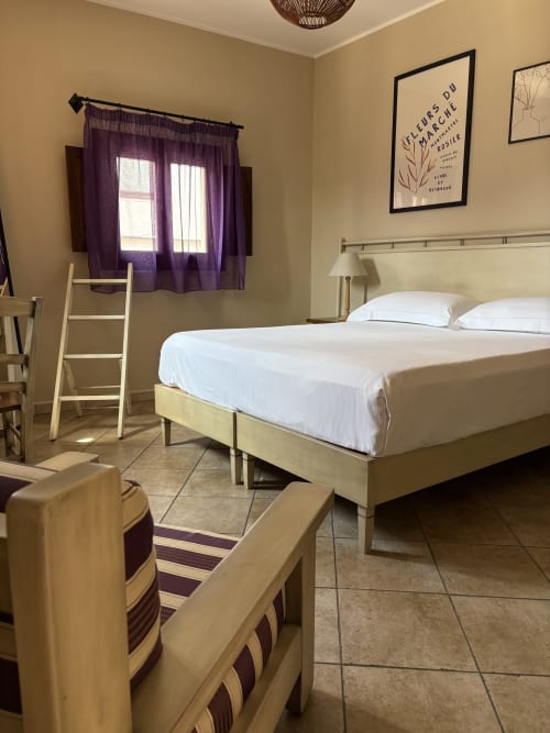 Camera da letto luminosa dell'appartamento Sicily In Home a Catania con letto matrimoniale, tende viola e arredi moderni