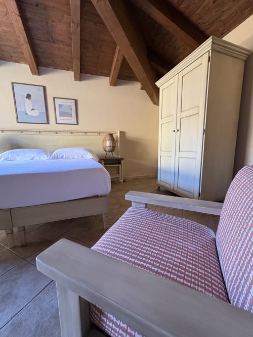 Camera da letto Almarina a Sicily In Home con travi di legno a vista, armadio color crema, biancheria blu e letto con motivi rossi