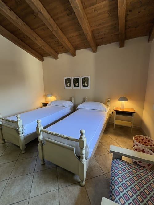 Due letti gemelli con strutture bianche e biancheria blu in una camera da letto di appartamento siciliano con travi in legno a vista