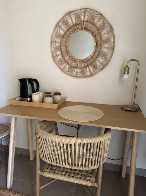 Espace de travail au Domaine d'Olga avec bureau en bois, chaise tressée, miroir en rotin et équipements d'accueil à Aniane