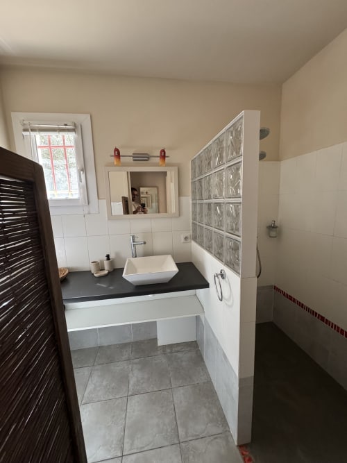 Salle de bain moderne avec lavabo, miroir et murs carrelés au Domaine d'Olga B&B à Aniane