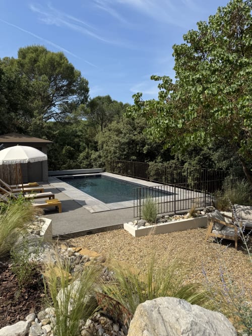 Terrasse piscine du Domaine d'Olga à Aniane avec transats, parasols et jardins méditerranéens surplombant la forêt