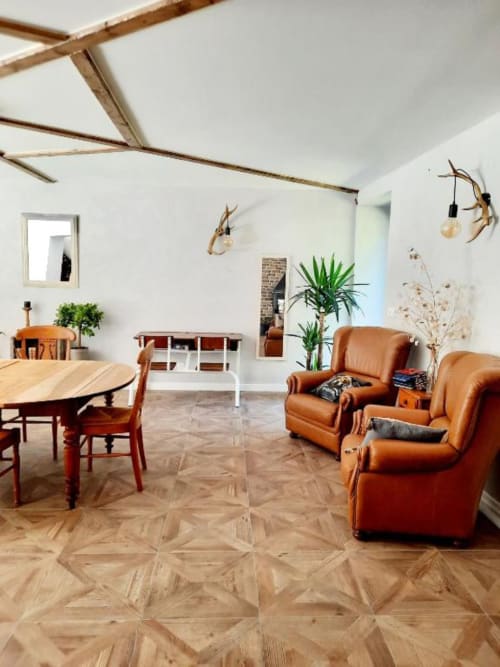 Spacieux séjour du gîte Le Petit Bégou à Saint-Auban-d'Oze avec parquet chevrons, fauteuils en cuir cognac, style rustique