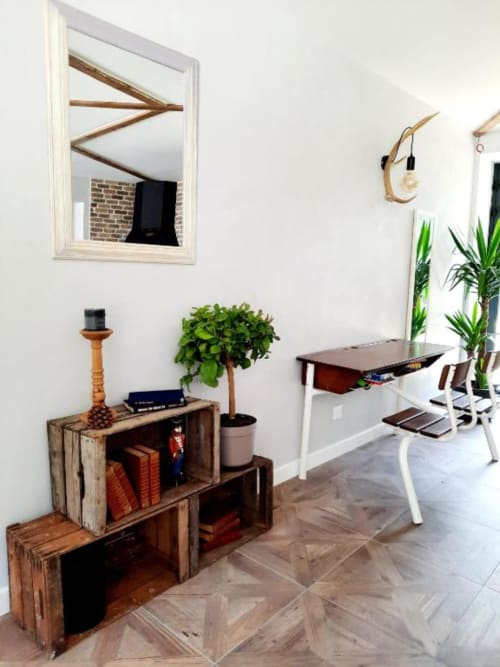 Espace de travail moderne au B&B Le Petit Bégou avec bureau, rangement caisse bois, plante en pot et miroir encadré