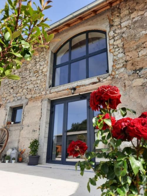 Entrée du Petit Bégou avec roses rouges et baies vitrées modernes à Saint-Auban-d'Oze