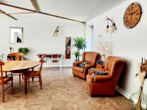 Spacieux séjour du Gîte Le Petit Bégou avec fauteuils cuir, table à manger en bois et décor rustique à Saint-Auban-d'Oze