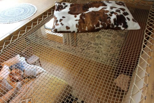 Chambre douillette au Le Petit Bégou avec parc à filet, coussin à motif vache et assiette décorative à Saint-Auban-d'Oze