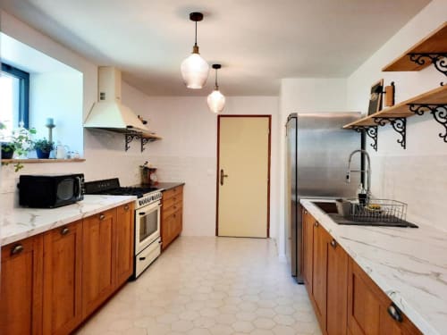 Cuisine ouverte moderne du gîte Le Petit Bégou avec meubles en bois, comptoirs en marbre et luminaires suspendus