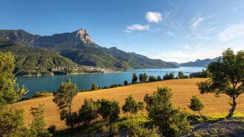 Vue alpine du lac avec montagnes et champs dorés au Petit Bégou à Saint-Auban-d'Oze