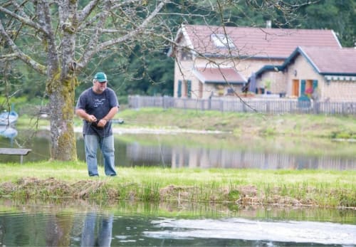 Homme pêchant près de l'étang à Villa Pré d'Oro à Amage, France avec ferme et arbres en arrière-plan