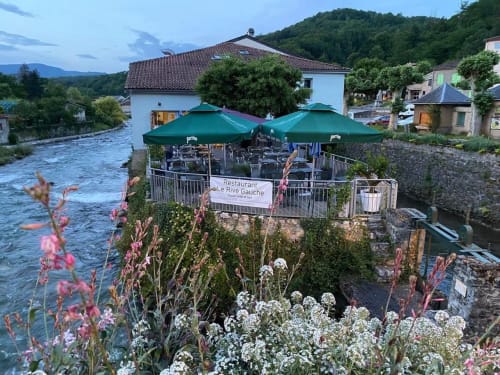 Le restaurant Rive Gauche avec ses parasols verts surplombant la rivière à Seix, en France