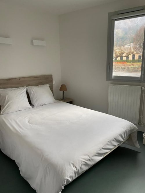 Chambre moderne et épurée à la Maison Du Haut Salat à Seix avec literie blanche, tête de lit en bois et vue sur la campagne