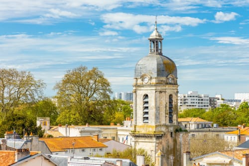 La tour clocher historique domine Le Langon avec le feuillage printanier et le ciel bleu de L'Écrin des Roches