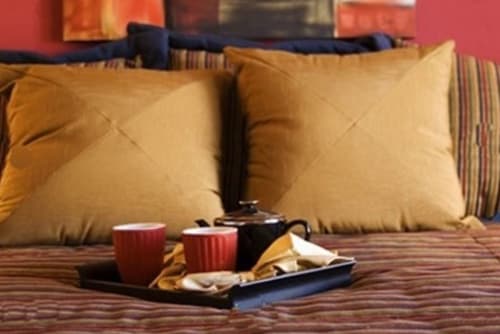Accogliente camera da letto a Parioli House con cuscini dorati, biancheria a righe e servizio di tè mattutino sul comodino