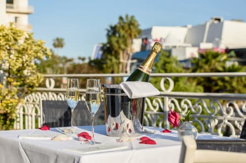 Champagnerflasche im Eiskühler mit Gläsern und Rosenblättern auf der eleganten Terrasse des Hotels Splendid Cannes