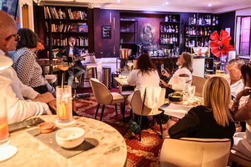 Elegantes Esszimmer des Hotel Splendid Cannes mit Gästen, Bar, Bücherregalen und violetter Ambientebeleuchtung