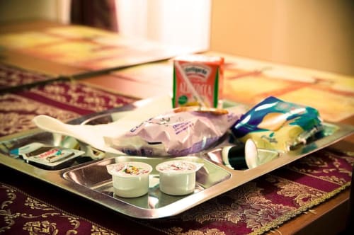 Vassoio di benvenuto della Parioli House con yogurt, snack e amenities su panno a motivi bordeaux